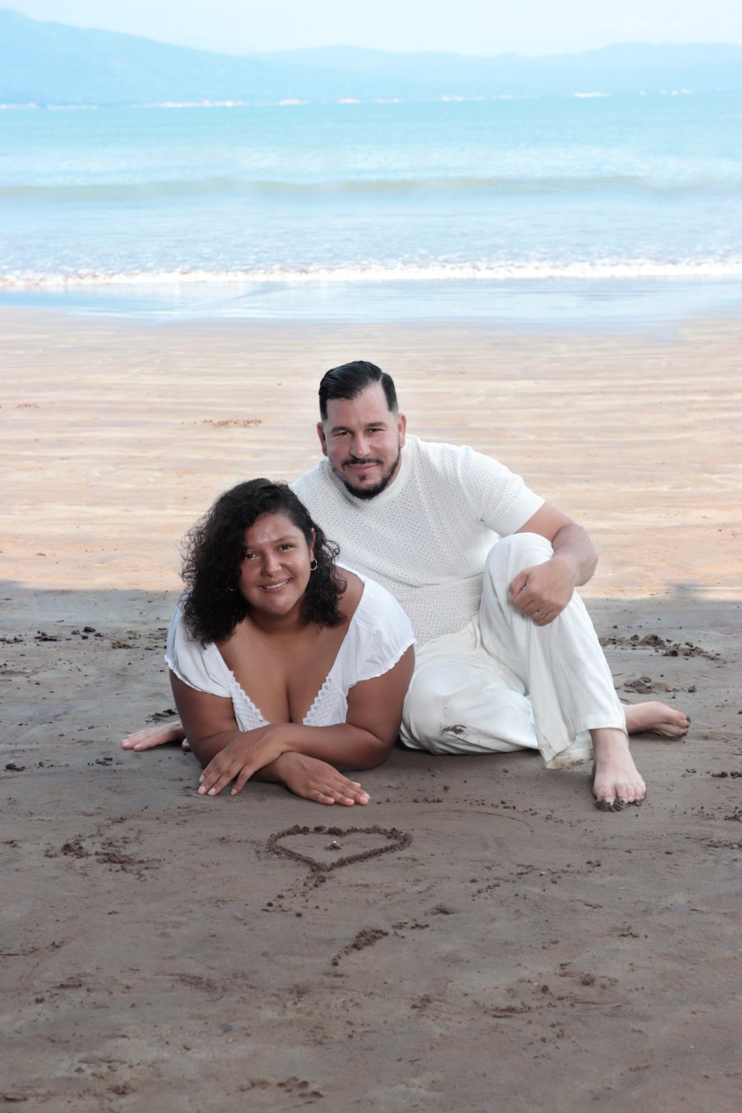 Cinthya y Adriel juntos en la playa junto a un corazón dibujado en la arena
